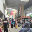 Big crowd outside of a venue with a visible red foodtruck in the distance